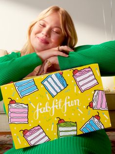 a woman is holding up a box with cakes on it that says, happy birthday