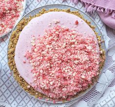 a pie with pink frosting and sprinkles sitting on top of a table