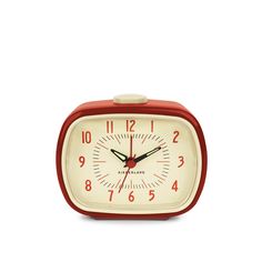 a red and white alarm clock sitting on top of a table