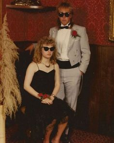 a man and woman dressed up in formal wear standing next to each other with sunglasses on