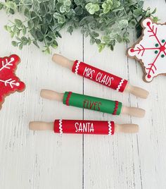 three wooden rolling moulders decorated with christmas decorations and words on them, sitting next to some cookies