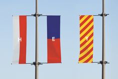 three flags with the letters h e and h e on them are hanging in front of a blue sky