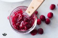 raspberry jam in a jar with a wooden spoon