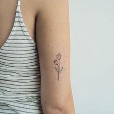 a woman's arm with a single flower tattoo on the left side of her arm