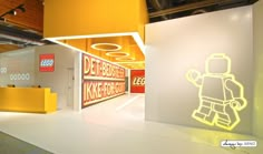 a lego store with yellow and white lighting on the walls, an open door leading to another room