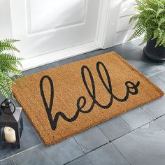 a door mat with the word hello written on it next to a potted plant