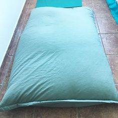 a green pillow sitting on top of a floor next to a blue blanket and pillows