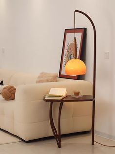 a white couch sitting next to a table with a lamp on it's side