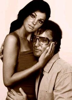 a man is hugging a woman's head with her arm around her neck and she has glasses on