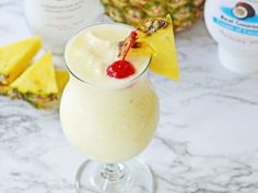 a pineapple smoothie in a glass with a cherry on top