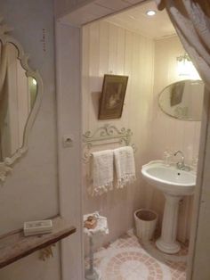 a bathroom with a sink, mirror and toilet paper roll on the floor next to it