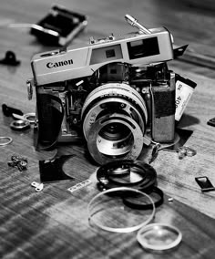 an old camera sitting on top of a wooden table next to other broken up objects