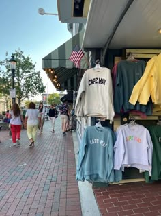 people walk past clothing on display in front of a store