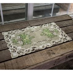 a table with a white doily on top of wooden planks and windows in the background