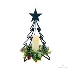 a candle is lit in front of a christmas tree ornament with leaves and berries