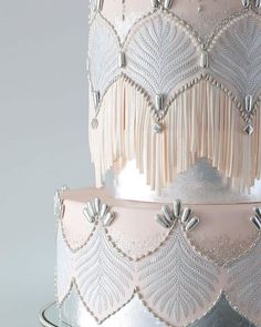 a three tiered cake with white frosting and beaded fringes on top