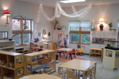 a classroom with tables, chairs and shelves filled with children's toys in it