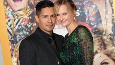 a man and woman standing next to each other in front of a wall with movie posters on it