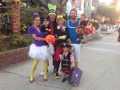 a group of people dressed in costumes posing for a photo on the sidewalk with their children