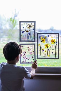 a young boy is looking out the window at wildflowers and daisies on display