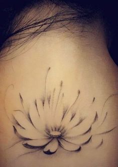 the back of a woman's neck with a flower tattoo on her left side