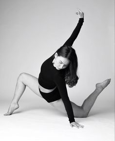 a woman in black leotard and tights is posing on the floor with her legs spread out