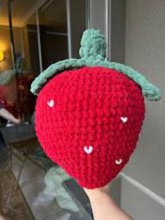 someone is holding up a crocheted strawberry hat