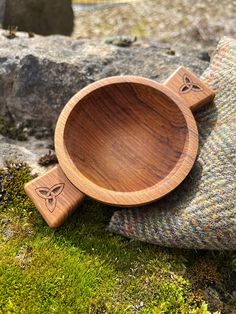 a wooden bowl sitting on top of a moss covered rock