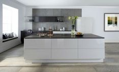 a modern kitchen with white cabinets and black counter tops, along with gray tile flooring