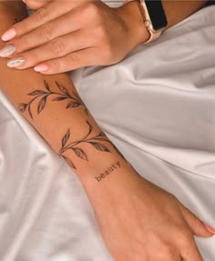 a woman's arm with a tattoo that says beauty on it, and leaves