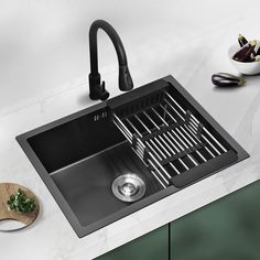 a kitchen sink with a black faucet on the counter top next to a cutting board