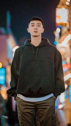 a young man standing in the middle of a street at night wearing a black hoodie