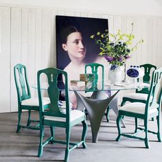 a dining room table with chairs and a painting on the wall in the back ground