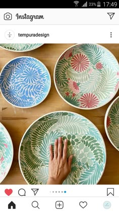 four plates with different designs on them, one being painted by someone's hand