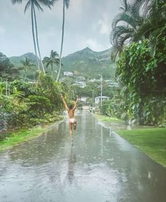 a woman is dancing in the rain on a road