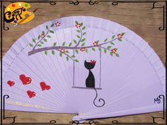 a white fan with a black cat sitting on a tree branch and hearts hanging from it