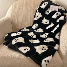 a black and white blanket with ghost faces on it sitting on a chair next to a wall