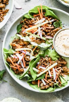 lettuce wraps filled with ground beef, carrots and dressing on a plate