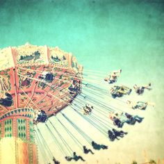 an old photo of a carnival ride with birds flying around the ride and people riding on it