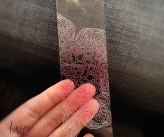 a person is holding up a piece of paper with designs on it in their hand