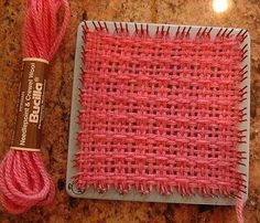 a piece of pink yarn next to a spool of red thread on a counter