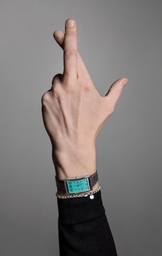 a person's hand with a wrist watch on it, making the middle finger sign