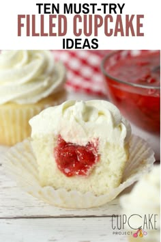 cupcakes with white frosting and strawberries in the middle, on a wooden table