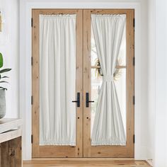 a pair of doors with curtains on them in front of a potted houseplant