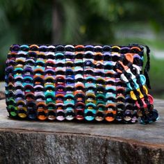 a multicolored purse sitting on top of a tree stump