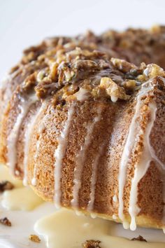 a bundt cake with icing and walnuts on top sitting on a plate