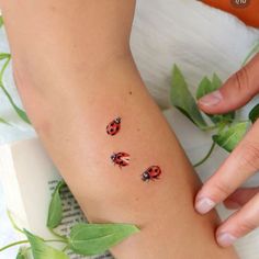 ladybugs tattoo on the left side of the leg and right arm, with leaves surrounding them