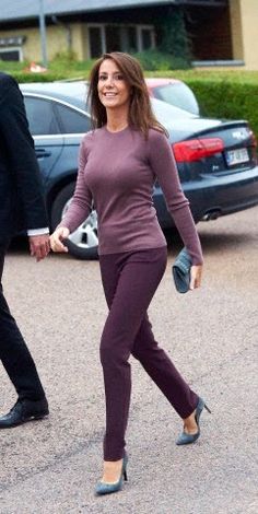 a man and woman are walking in the parking lot holding hands, both wearing purple pants