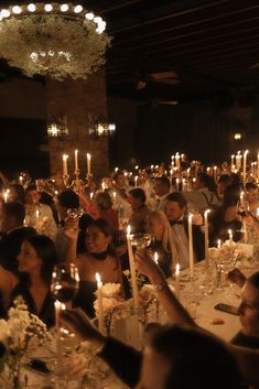 a large group of people sitting at tables with candles in their hands