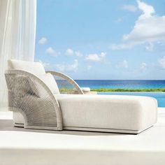 a white chaise lounge chair next to an ocean view